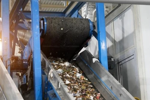 Worker guiding steel sheets on a conveyor bed in a workshop